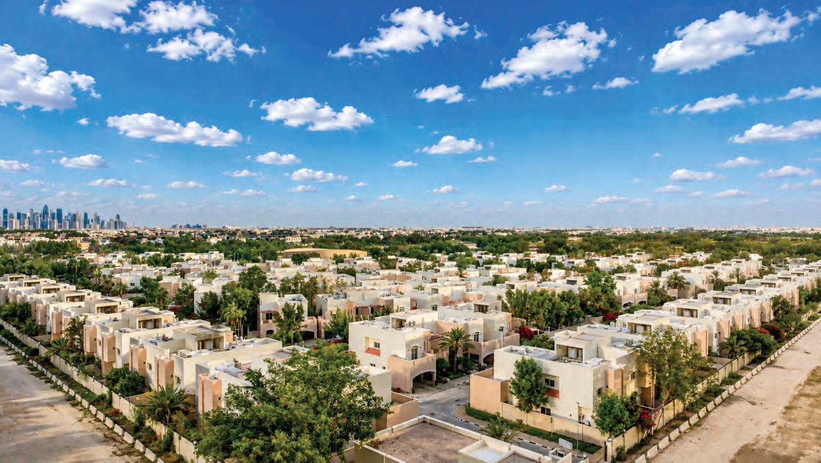 Tree-lined streets of the compound with the West Bay skyline behind